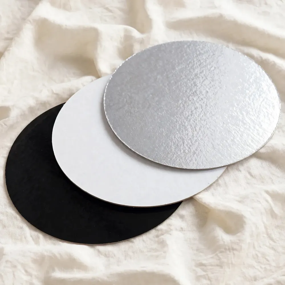 Black, white, and silver round cake boards fanned on ivory linen